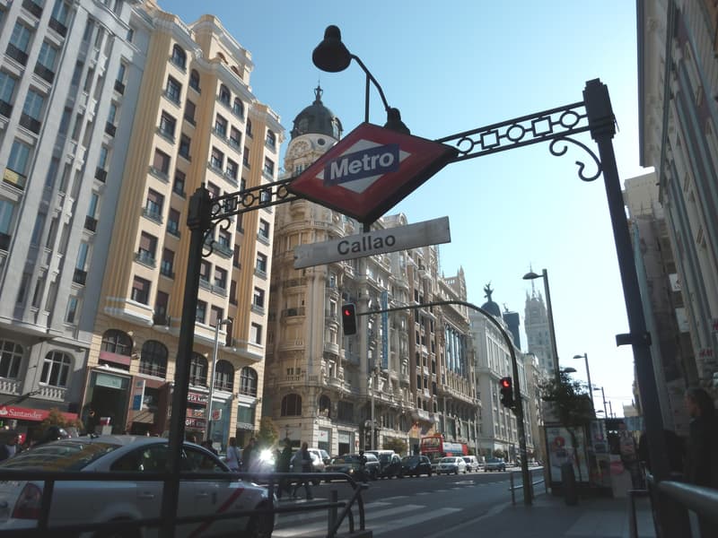 Gran Via at Callao in Madrid, with traffic, pedestrians and the Metro sign above the street